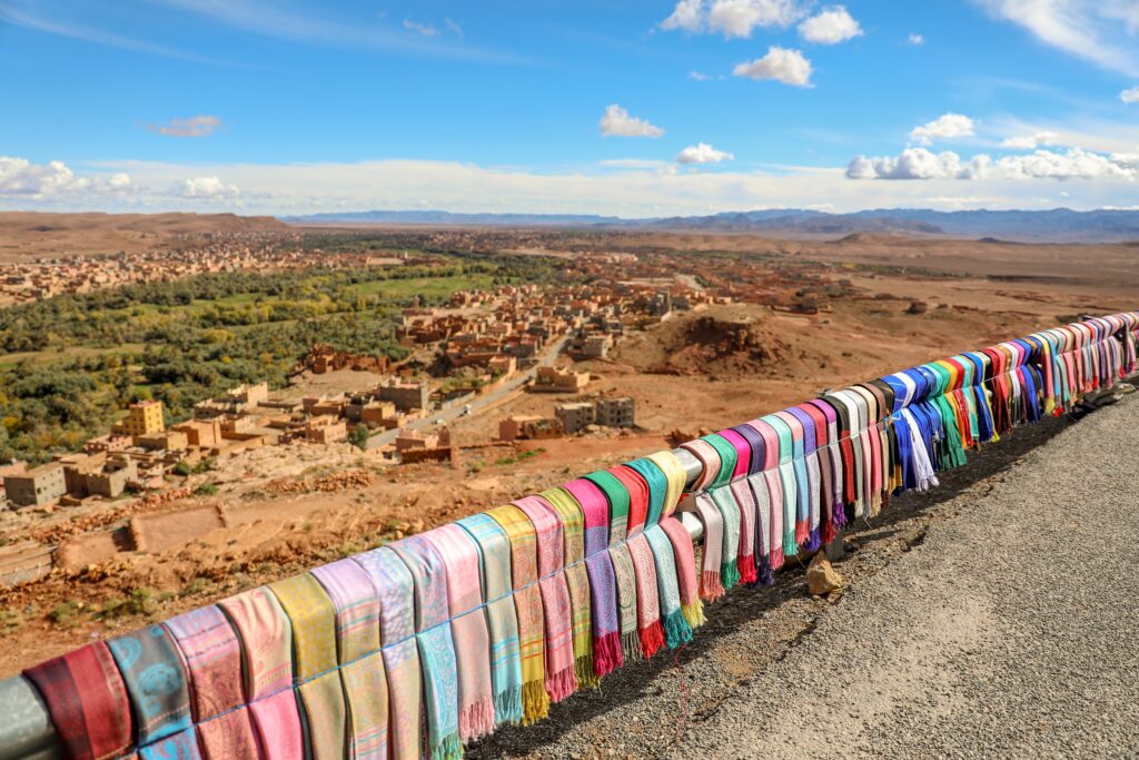 Colorful scarves on a guardrail overlooking a brown adobe landscape