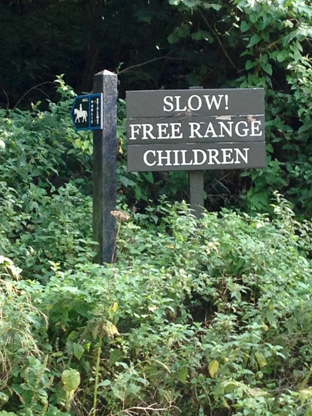 Sign nestled in outside greenery reads Slow Free Range Children