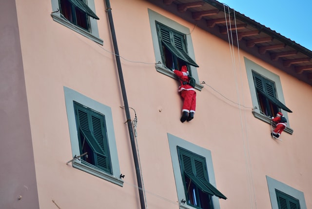 Two santas climbing into a building's windows