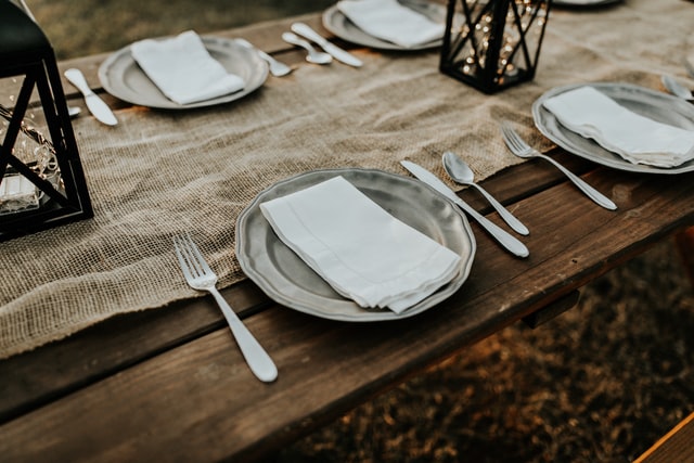 Table set with plates, knives, forks, and napkins minus food 